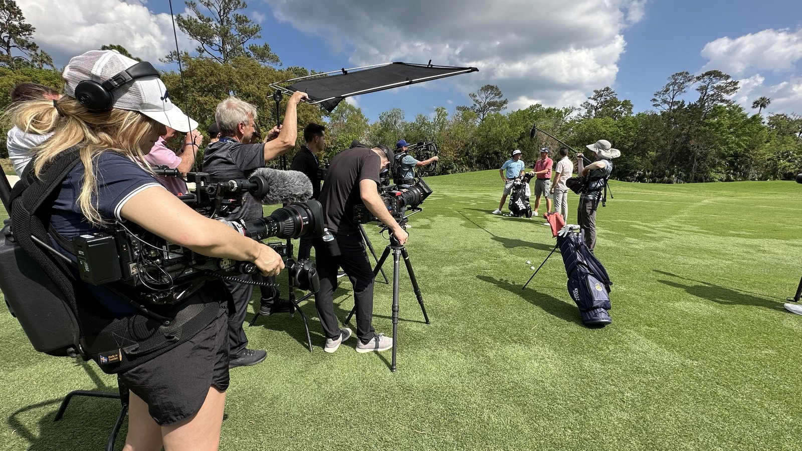 A film crew, including Josh Nagel, filming golfers on a course during production of Netflix's Full Swing.