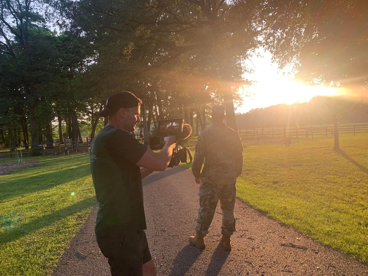 Josh Nagel filming a service member outdoors at golden hour on a rural path, during production of H.O.O.V.E.S.: Healing Our Veterans.